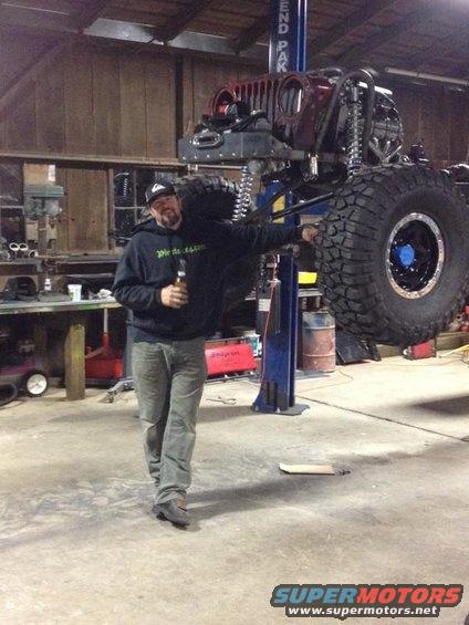 Man in garage next to a lifted 1985 Jeep CJ7 with large tires