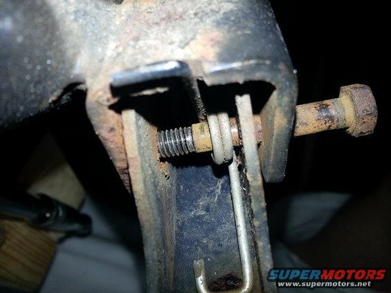 Close-up of a rusted metal bracket with a bolt and washer