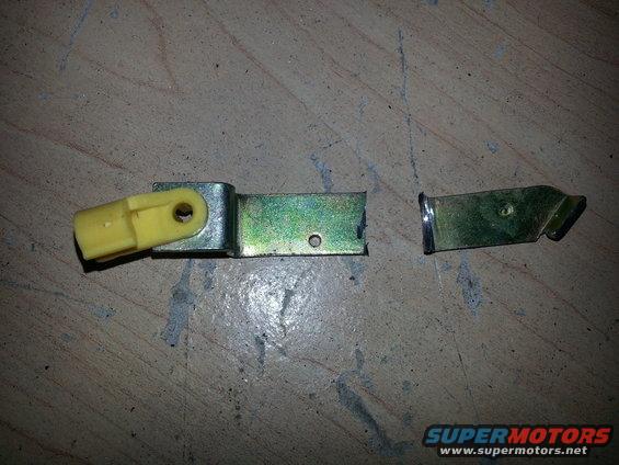 Broken tailgate latch mechanism with yellow plastic component and two metal pieces