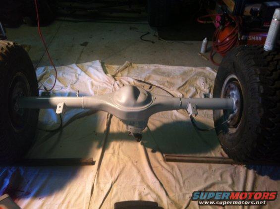 rear axle assembly with two tires attached, laid out on a drop cloth