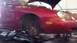 1996 Ford Taurus - The front wheel of a red 1996 Ford Taurus is removed while the hood is open, indicating maintenance work.