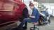 1996 Ford Taurus - Mechanic performing maintenance on a red car's front wheel in a workshop.