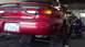 1996 Ford Taurus - A mechanic works on the rear brakes of a red 1996 Ford Taurus in a repair shop.