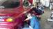 1996 Ford Taurus - Two mechanics are working on a red sedan in a garage, with a scooter visible in the background.