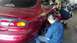 1996 Ford Taurus - Mechanic works on the rear wheel of a red 1996 Ford Taurus in a garage.