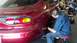 1996 Ford Taurus - A mechanic works on the rear wheel of a red Mazda RX-7 in a garage, with a scooter visible in the background.