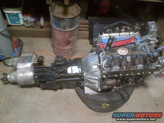 Engine and transmission assembly on a tire, with chains and red support bar