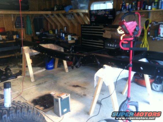 Vehicle frame on sawhorses in a garage with tools and equipment around