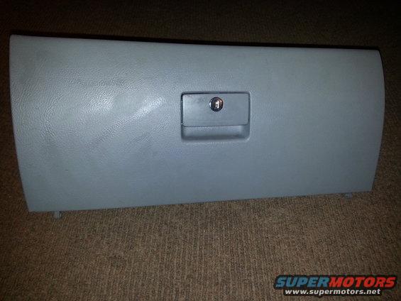 Gray plastic glove box door with a lock, resting on carpet