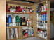 2004 Aston Martin Virage - A collection of automotive supplies, including oils, cleaners, and repair manuals, neatly organized on wooden shelves.