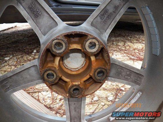 Close-up of a rusty car wheel hub with five lug nut holes and markings