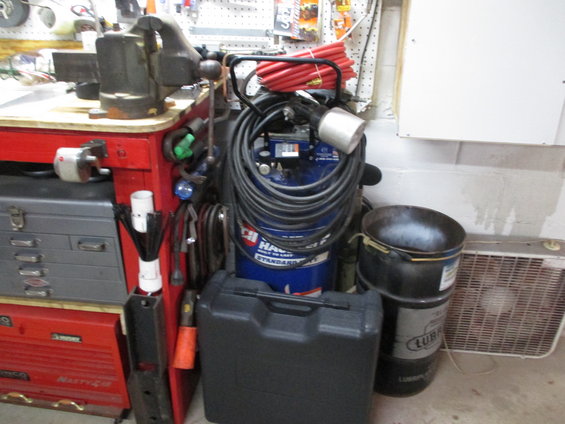 Red tool chest with gray drawers, blue air compressor with coiled hose, and a black case
