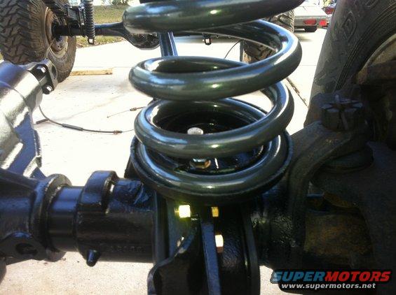 Close-up of a vehicle's front suspension coil spring and axle assembly