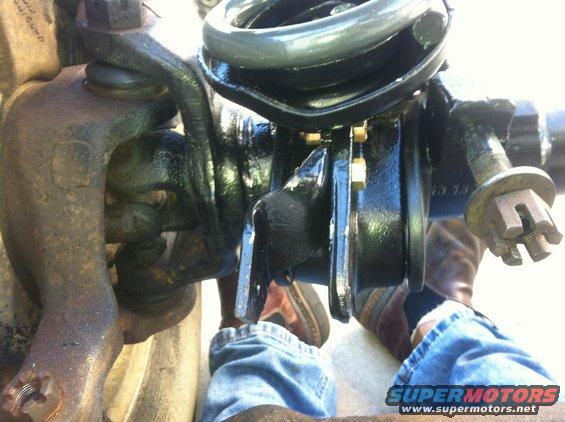 Close-up of a vehicle's front suspension assembly, showing the steering knuckle and coil spring