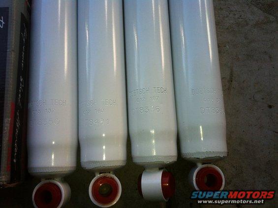 Four white Doetsch Tech shock absorbers with red bushings