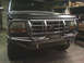 1989 Ford Bronco - Front view of a dark-colored Ford truck a custom metal bumper and grille guard.