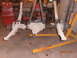 1988 Ford F-250 - A disassembled front axle assembly is shown, suspended by straps and a yellow engine hoist in a garage setting.