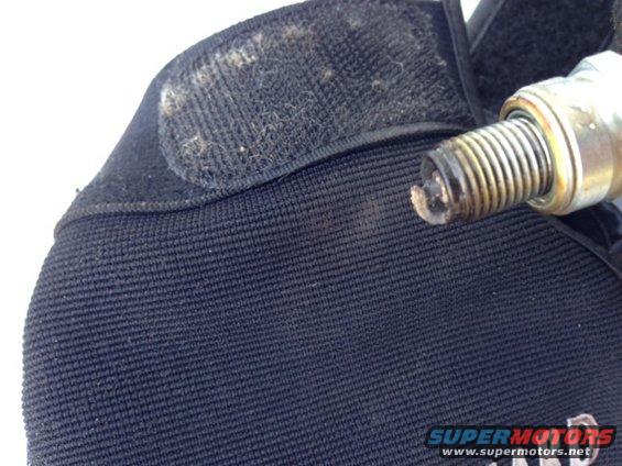 Close-up of a dirty spark plug held over black fabric