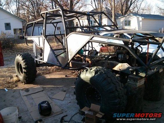 Custom off-road buggy frame with large tires and exposed engine, partially built
