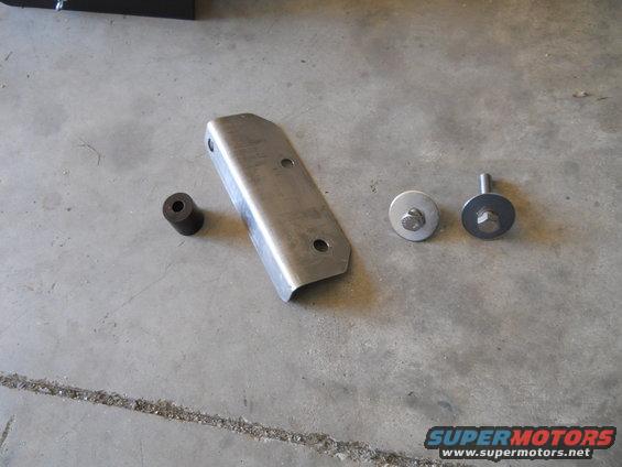 Metal bracket with two bolts and a rubber bushing on a concrete surface
