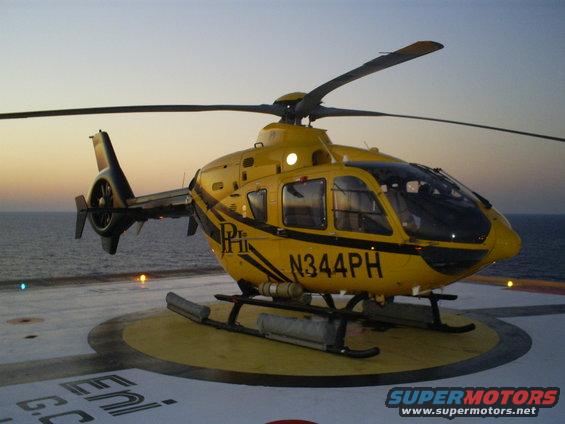 Yellow helicopter with N344PH registration on helipad at dusk