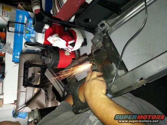 Close-up of a red and blue automotive part assembly with a hand holding a tool