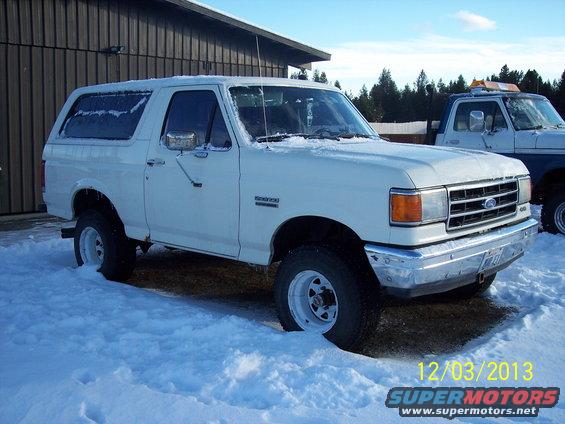 White Ford Bronco in snow, another truck behind it