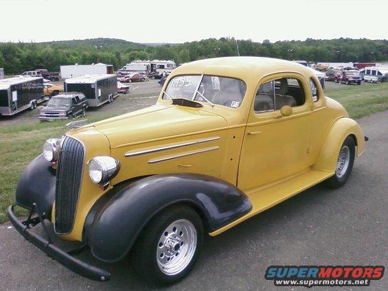 Yellow coupe with black fenders and chrome wheels. Windshield has '1935' written on it