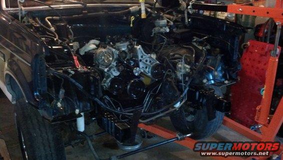 Engine bay with engine removed, showing bare frame and suspension components