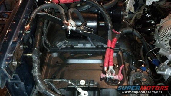 Engine bay showing battery terminals, red-coated wires, and black wiring harnesses