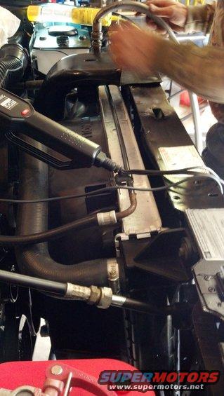 Radiator and hoses in engine bay, with a tool being used