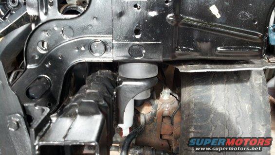 Close-up of vehicle frame and suspension parts, including a rubber mount and tire