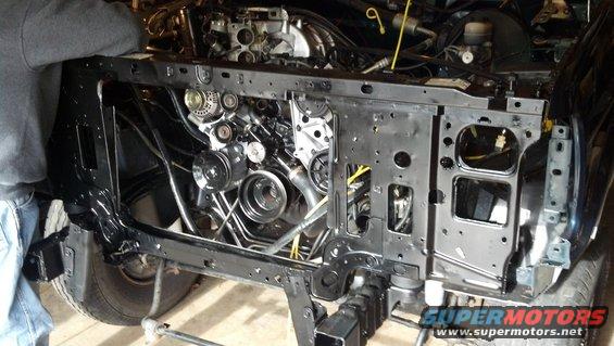 Front end of a vehicle with engine components visible, undergoing repair