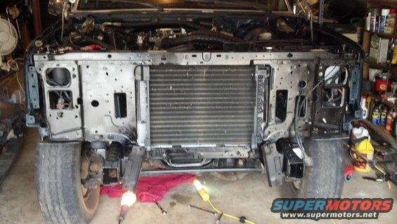 Front end of a dark green 1992 Ford Bronco with the grille and bumper removed, showing the radiator and engine components