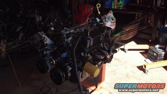 Engine assembly on an engine stand, with various tools and parts in the background