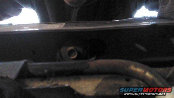 Close-up of a dark engine bay with a metal pipe and a bolt visible