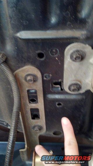 Close-up of hood latch mechanism with finger pointing