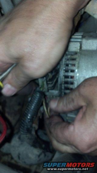 Hands connecting wires to a car alternator
