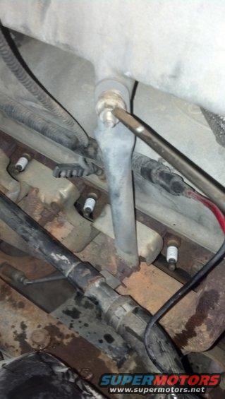 Engine block with spark plugs and hoses visible, some rust present