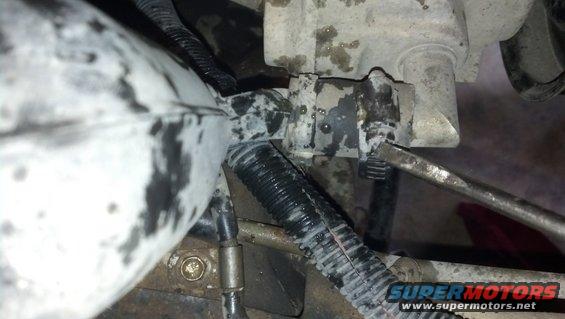 Close-up of a grimy engine component with a screwdriver