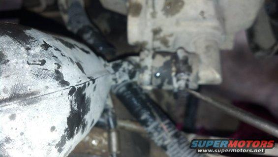 Close-up of a greasy engine component with hoses attached