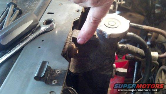 hand pointing at radiator cap and hoses, wrench and screwdriver nearby