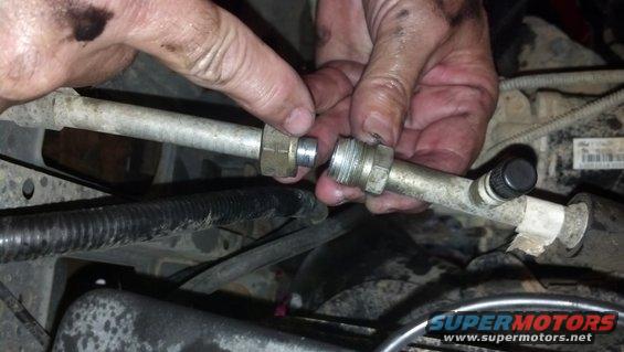 Hands disconnecting an automotive AC line with a black cap on one end