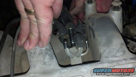 Hands working on fuel lines connected to an engine component