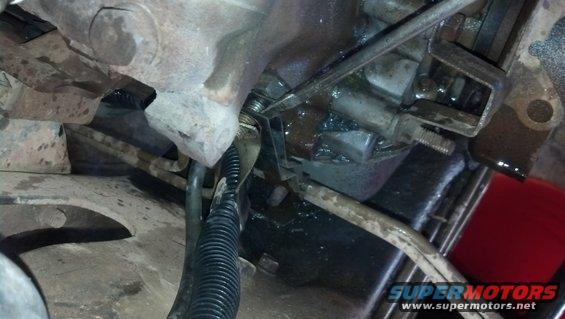 close-up of vehicle transmission linkage with some fluid visible