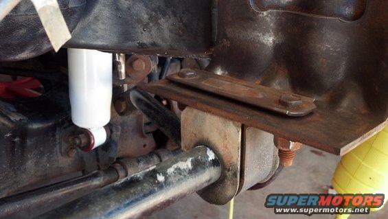 Close-up of a white shock absorber and rusty metal bracket on a vehicle's suspension