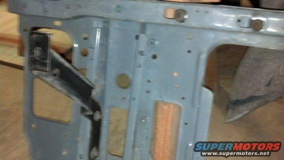 Close-up of a gray metal vehicle frame section with various holes and brackets