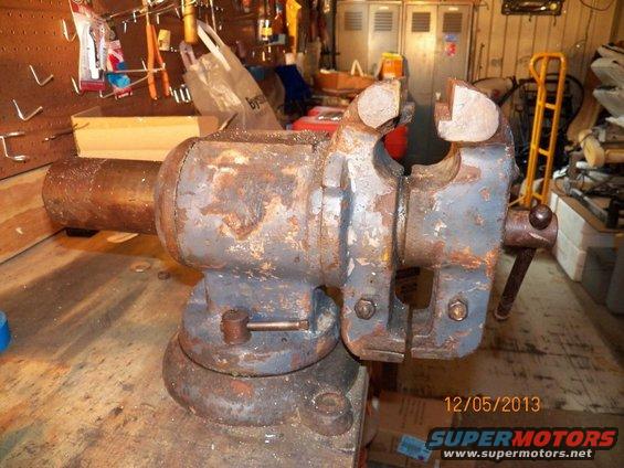 Bench vise on a workbench, showing rust and wear