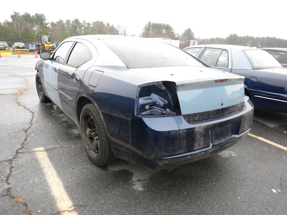 Blue sedan with light blue front fender and rear quarter panel, missing taillight, parked on wet asphalt
