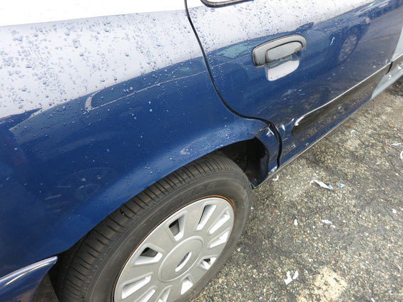 Blue sedan's rear wheel well and dented door, 1991 Ford Crown Victoria LTD